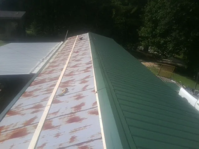 Old rusted panels beside newly installed green metal roofing — Wind Damage Roof Repair by Roofing Brothers in Lake Junaluska