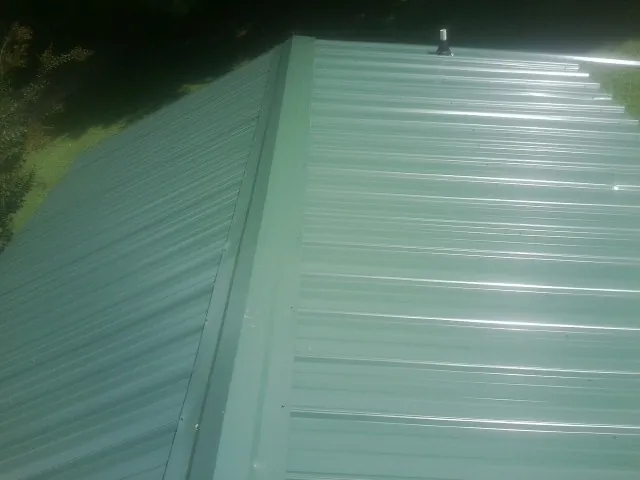 New green metal panels meeting at the ridge of a roof — Flat Roof Repair work by our crew in Lake Junaluska