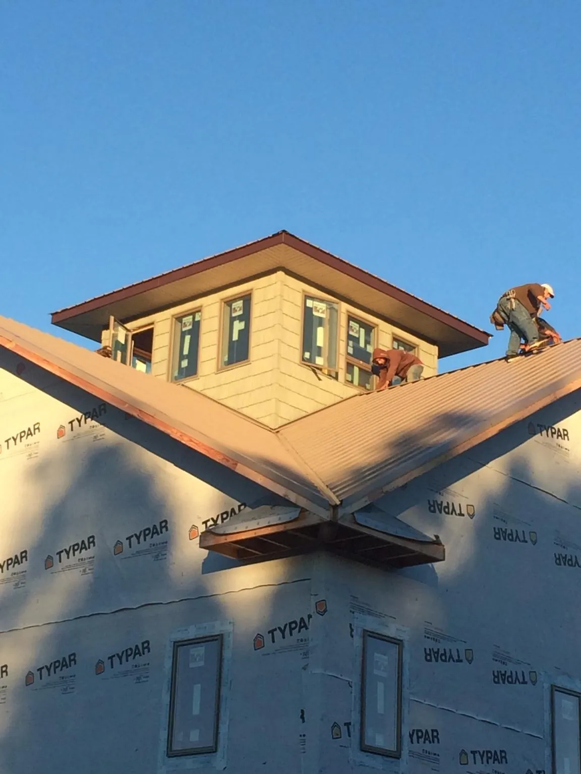 Roofers working around a rooftop cupola on a new metal roof at sunset — Roof Waterproofing in Lake Junaluska by Roofing Brothers